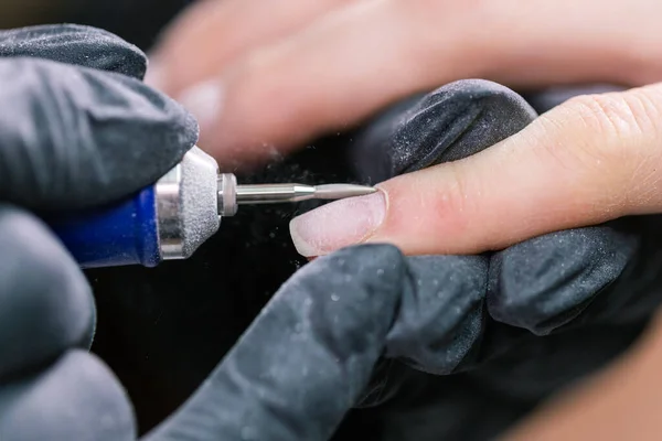 Kobieta używa elektrycznego wiertarki do paznokci w salonie piękności. Proces manicure paznokcie szczegółowo. Pomysł na lakierowanie żelowe. — Zdjęcie stockowe