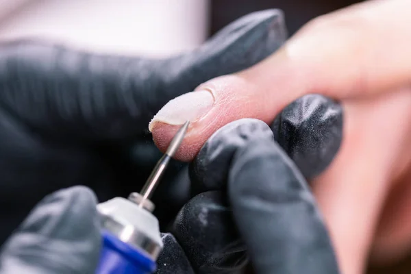 Kvinnan använder elektrisk nagelfilsborr i skönhetssalong. Naglar manikyr process i detalj. Gel polish närbild koncept. — Stockfoto