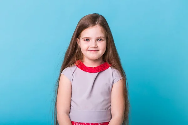 Hermosa niña aislada sobre un fondo azul. Concepto de la infancia y los niños . — Foto de Stock