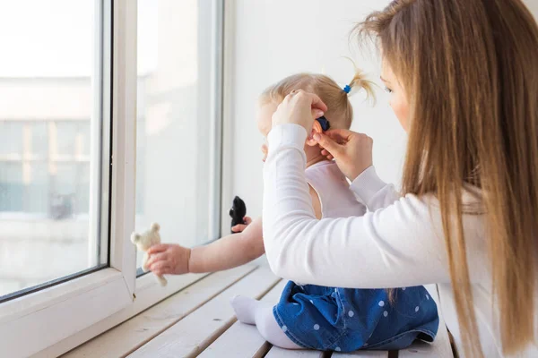 Hearing aid in baby girls ear. Toddler child wearing a hearing aid at home. Disabled child, disability and deafness concept.