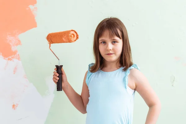 Apartmanda tamirat var. Mutlu çocuk duvarı turuncu boyayla boyuyor. Yenileme ve dekorasyon konsepti. — Stok fotoğraf