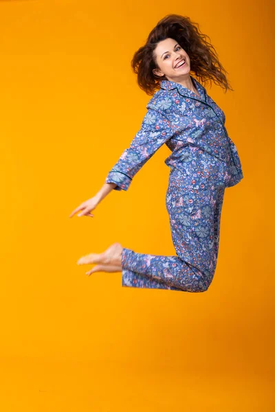 Chica joven sonriente en pijama ropa de casa posando mientras descansa en casa aislado en retrato de estudio de fondo amarillo. Relajarse concepto de buen humor estilo de vida . — Foto de Stock