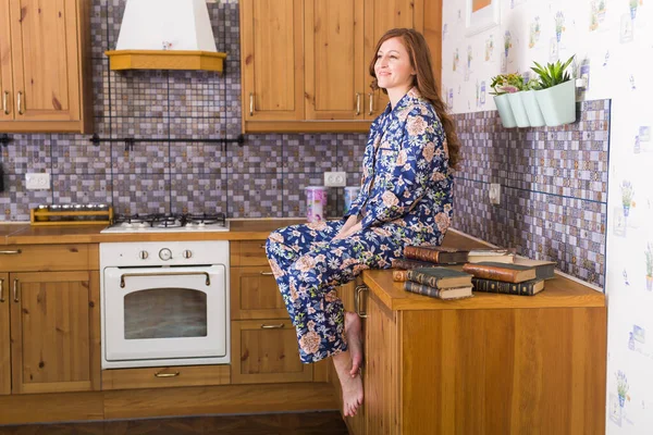 Genç kızıl saçlı kadın evde kitaplarla rahatlıyor. Karantina, izolasyon, koronavirüs salgını. Evde kal.. — Stok fotoğraf