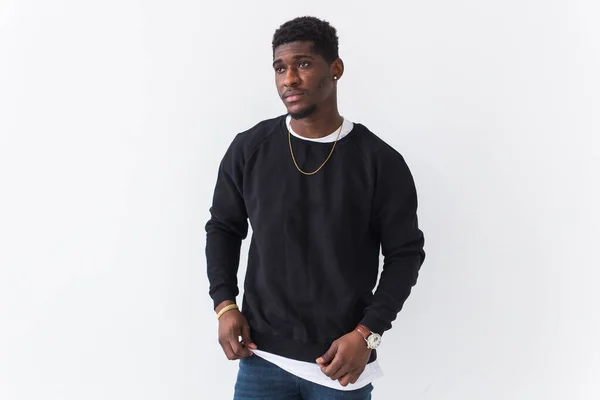 Portrait handsome young black man dressed in jeans and sweatshirt on white background. Street fashion and modern youth culture. — Stock Photo, Image