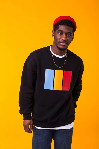 Jeugd straat mode concept - Portret van zelfverzekerde sexy zwarte man in stijlvolle sweater op gele achtergrond. — Stockfoto