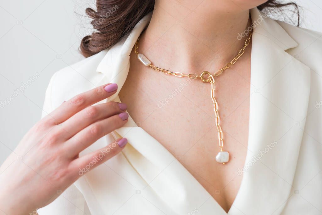 Close-up of woman wearing a gold necklace. Jewelry, bijouterie and accessories concept.