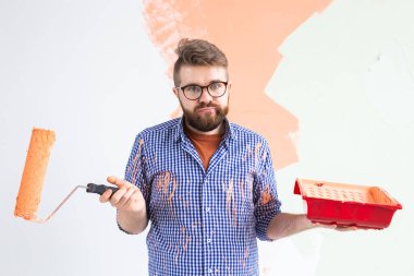 Üzgün adam evin iç duvarını boyuyor. Yenileme, onarım ve yeniden dekorasyon konsepti.