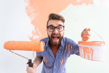 Yeni evin duvarlarını boyayan komik adam. Yenileme, onarım ve yeniden dekorasyon konsepti.
