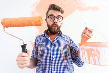 Yeni evdeki boya silindiriyle iç duvarı boyayan komik bir adam. Duvara boya süren patenli bir adam..