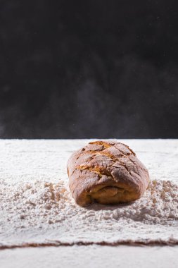 Geleneksel zanaatkar çavdar ekmeği unun içine düşer. Karanlık arka plan. Fırın ve ev yapımı kır ekmeği konsepti.