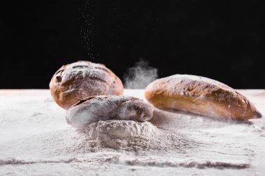 Geleneksel zanaatkar çavdar ekmeği unun içine düşer. Karanlık arka plan. Fırın ve ev yapımı kır ekmeği konsepti.