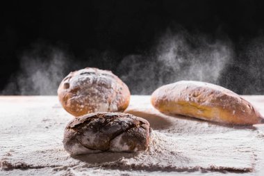 Geleneksel zanaatkar çavdar ekmeği unun içine düşer. Karanlık arka plan. Fırın ve ev yapımı kır ekmeği konsepti.