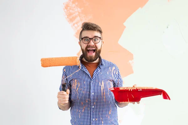 Yeni evin duvarlarını boyayan komik adam. Yenileme, onarım ve yeniden dekorasyon konsepti.