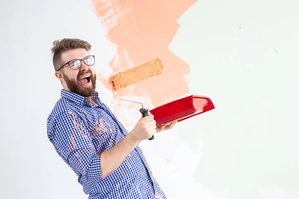 Repair in the apartment. Funny man paints the wall with paint. — Stock Photo, Image