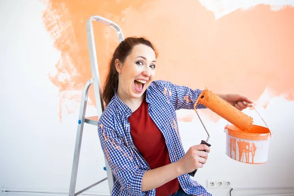 Renovation, redecoration and repair concept - Funny woman painting wall in new home. — Stock Photo, Image