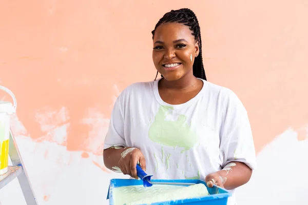 Молода афроамериканська жінка малює стіни в своїй новій квартирі. Поняття відновлення і прикраси. — стокове фото