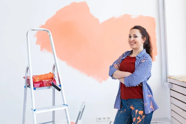 Hermosa mujer pintando la pared. Concepto de renovación, redecoración y reparación. — Foto de Stock