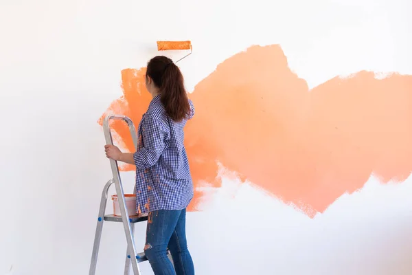 Yeni dairesinde duvar boyayan mutlu genç bir kadın. Tadilat, dekorasyon ve onarım. Boşluğu kopyala. — Stok fotoğraf