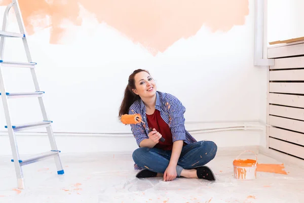 Renovation, redecoration and repair concept - Cheerful woman painting wall in new home. — Stock Photo, Image
