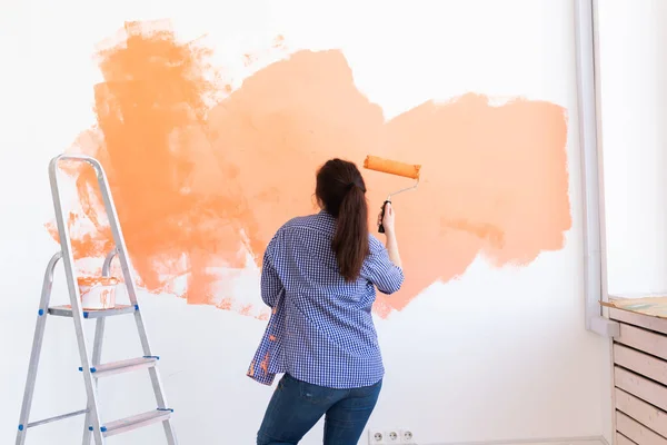 Ballando divertente donna pittura parete interna con rullo di vernice in nuova casa. Una donna con rullo che applica vernice su un muro . — Foto Stock
