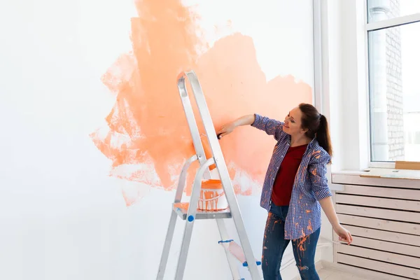 Pretty young woman with painting roller indoors. Redecoration, renovation, apartment repair and refreshment concept. — Stock Photo, Image