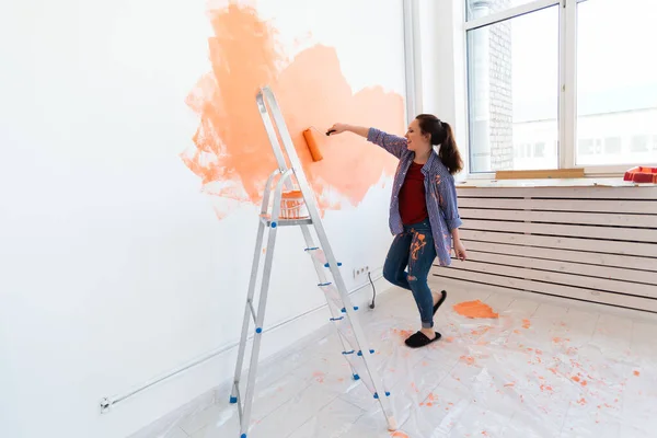 Bella donna pittura muro nel suo nuovo appartamento. Concetto di ristrutturazione e ridecorazione. — Foto Stock