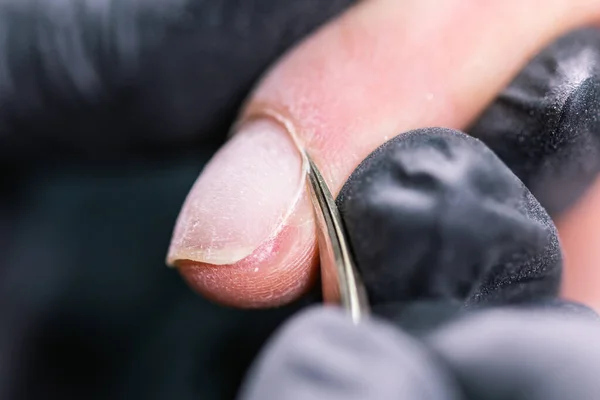 Манікюрник використовує електричний дриль для нігтів в салоні краси. Ідеальний манікюр нігтів крупним планом зі спалахом літаючого сміття . — стокове фото