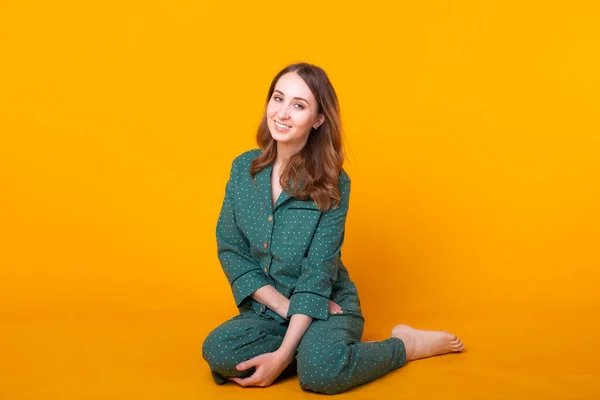 Lächelndes junges Mädchen im Schlafanzug posiert zu Hause isoliert auf gelbem Hintergrund im Studioporträt. Entspannen Sie sich bei guter Laune. — Stockfoto