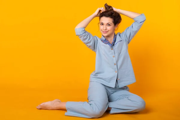 Lächelndes junges Mädchen im Schlafanzug posiert zu Hause isoliert auf gelbem Hintergrund im Studioporträt. Entspannen Sie sich bei guter Laune. — Stockfoto