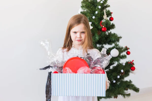 Umweltschutz- und Umweltschutzkonzept. Überraschte Kinderträgerbox mit Plastikmüll über Christbaumhintergrund. — Stockfoto