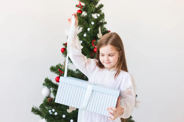 Mädchen öffnet Geschenkbox neben Weihnachtsbaum Feiertage, Weihnachten und Geschenke. — Stockfoto