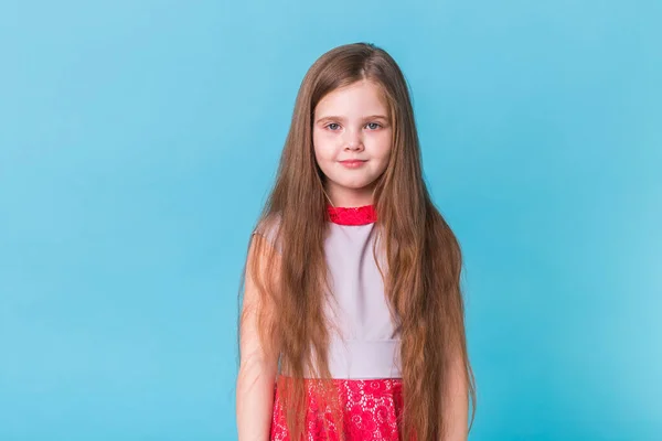 Hermosa niña aislada sobre un fondo azul con espacio para copiar. Concepto de la infancia y los niños . — Foto de Stock