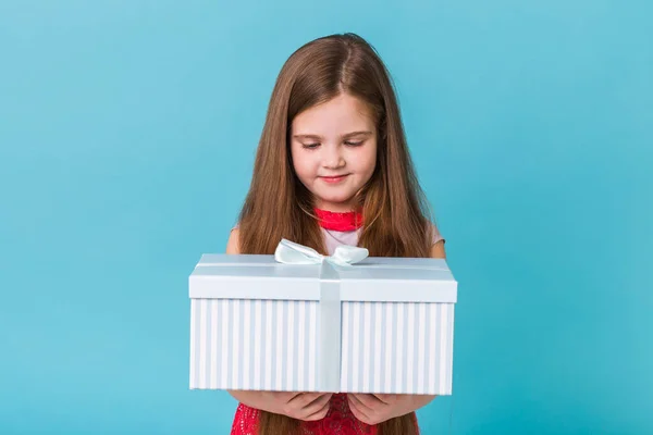Urlaub, Geschenke, Weihnachten, Kindheit und Geburtstag Konzept - lächelndes kleines Mädchen mit Geschenkbox über blauem Hintergrund — Stockfoto