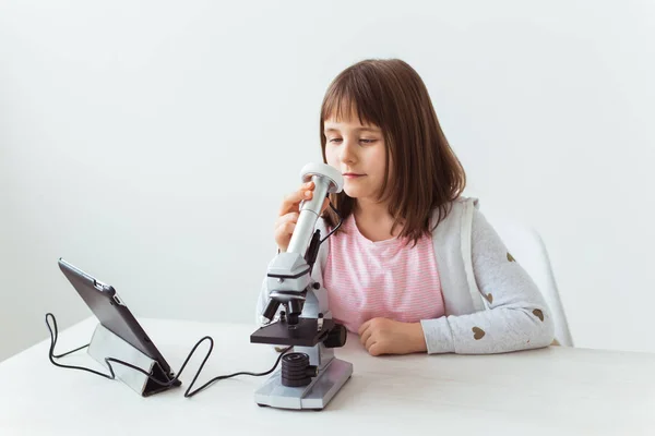 デジタル顕微鏡で宿題をしているかわいい子供の肖像画。テクノロジー、科学、子供の概念. — ストック写真