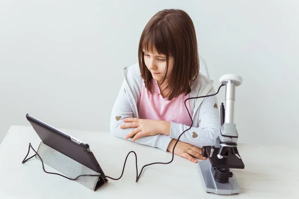 Colegiala usando microscopio en clase de ciencias. Tecnologías, lecciones y concepto infantil . —  Fotos de Stock