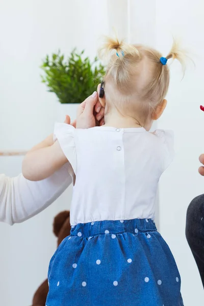 Audífono en el oído de las niñas. Niño pequeño usando un audífono en casa. Concepto de niño con discapacidad, discapacidad y sordera . — Foto de Stock