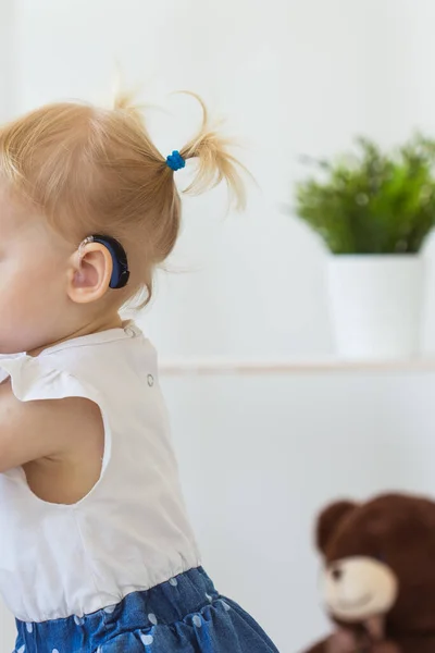 En liten flicka med hörapparat. Begreppet barn med funktionshinder, funktionshinder och dövhet. — Stockfoto