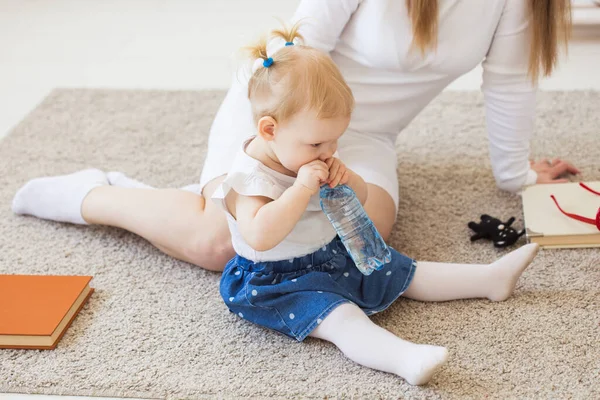 Liten småbarn flicka med flaska mineralvatten hemma. Barn- och familjebegreppet. — Stockfoto