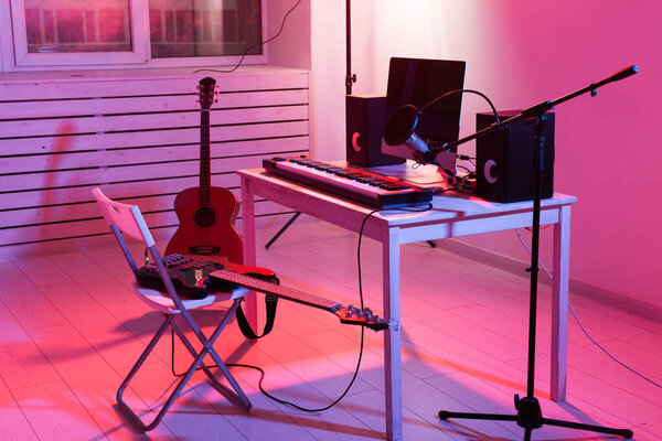 Microphone, computer and musical equipment guitars and piano background. Home recording studio concept.