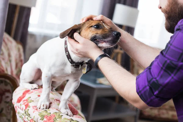 Feliz joven sentado con su perro en casa. Propietario de mascotas, animales y concepto de amistad . — Foto de Stock