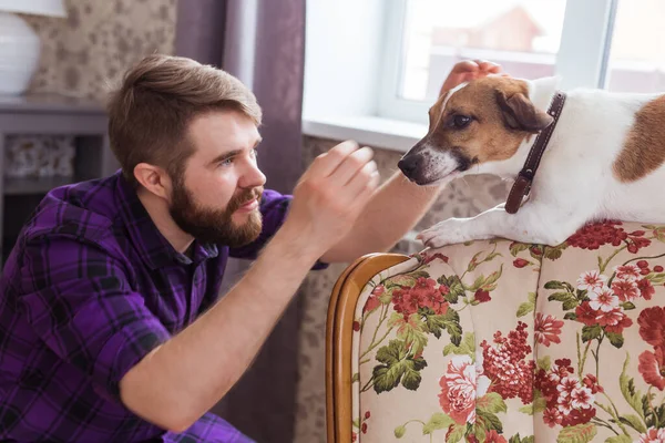 Primer plano retrato guapo joven hipster hombre juega y ama a su buen amigo perro en casa. Emociones humanas positivas, expresión facial, sentimientos . — Foto de Stock