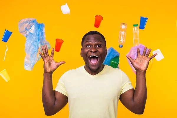 Problém recyklace plastů, ekologie a koncepce ekologických katastrof - Vyděšený muž křičí na žlutém pozadí odpadky. Bojí se ekologické katastrofy. — Stock fotografie
