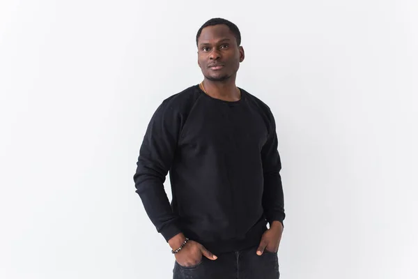 Portrait handsome young black man dressed in jeans and sweatshirt on white background. Street fashion and modern youth culture. — Stock Photo, Image