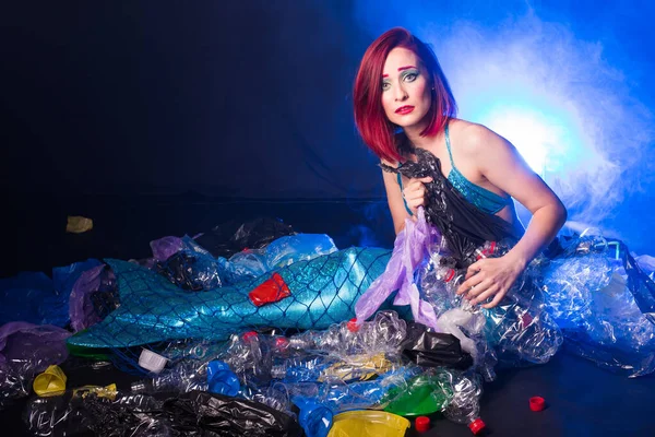 Fantasy mermaid in deep ocean sad because water pollution. Plastic trash and bottles pollution in ocean. Ecocatastrophe, garbage and plastic recycling concept.