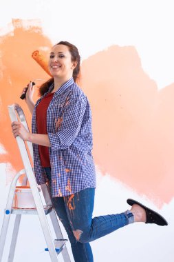 Yeni dairesinde duvar boyayan güzel bir kadın. Yenileme ve dekorasyon konsepti.