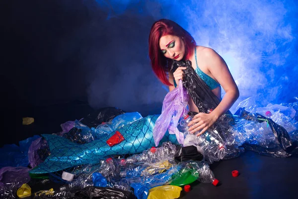Ocean plastic pollution. Cute mermaid swimming in water with plastic garbage. Stop plastic pollution. Fairy tale and reality concept.
