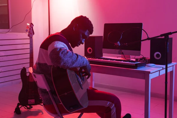 Create music and a recording studio concept - african american man guitarist recording electric guitar track in home studio