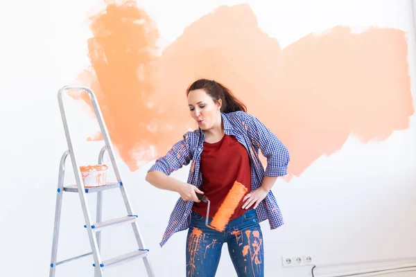 Bailando mujer divertida pintando pared. Concepto de renovación, redecoración y reparación . — Foto de Stock