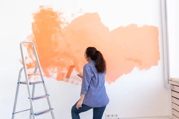 Donna allegra che dipinge i muri della nuova casa. Concetto di ristrutturazione, riparazione e ridecorazione. — Foto Stock