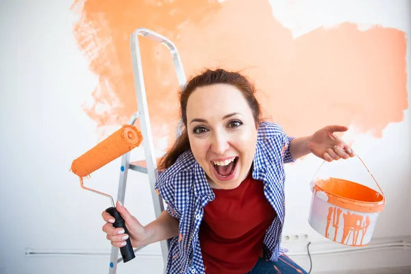 Joven mujer divertida pintando la pared en su nuevo apartamento. Concepto de renovación, redecoración y reparación . — Foto de Stock